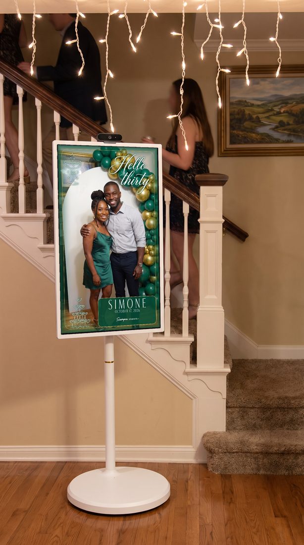 The Siempre kiosk: a white rolling stand with a portrait touchscreen showing a framed guest photo